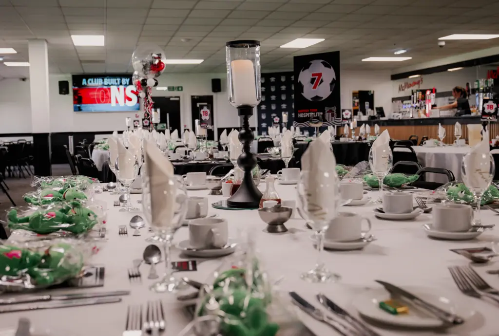 McMenemy's set up for an event showing crockery and cutlery with wreaths and wine glasses